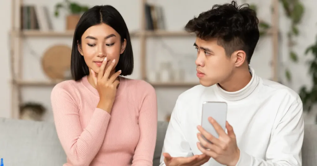 Couple where one is holding a phone looking hurt and the other has a face of how to I respond.