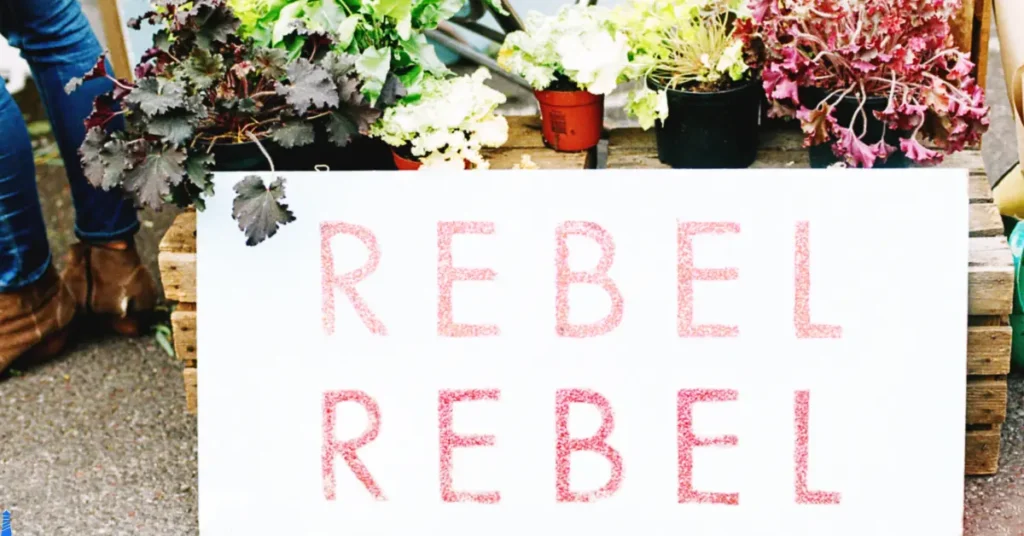 The words of rebel, rebel in front of flowers.
