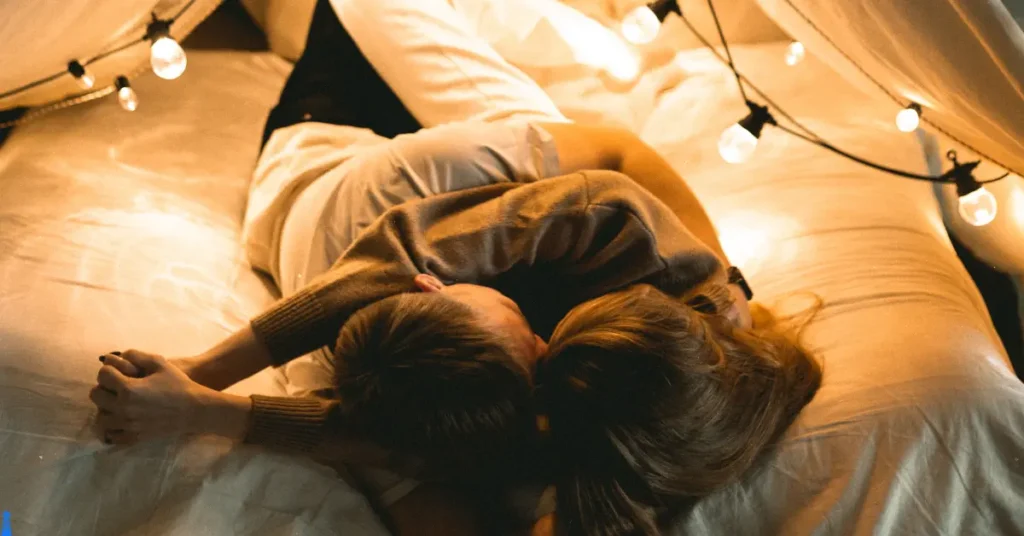 Couple cuddling in a blanket fort lit by Edison style lightbulbs.