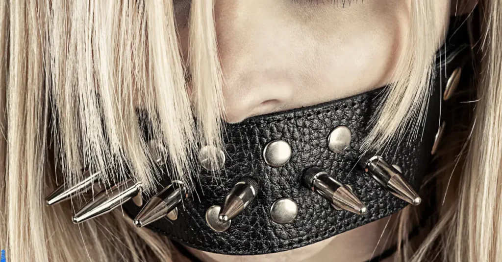 Mouth covered by a studded leather gag.