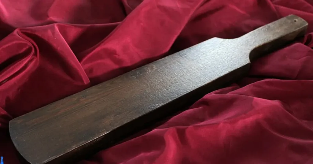 Wooden spanking paddle on a red background.