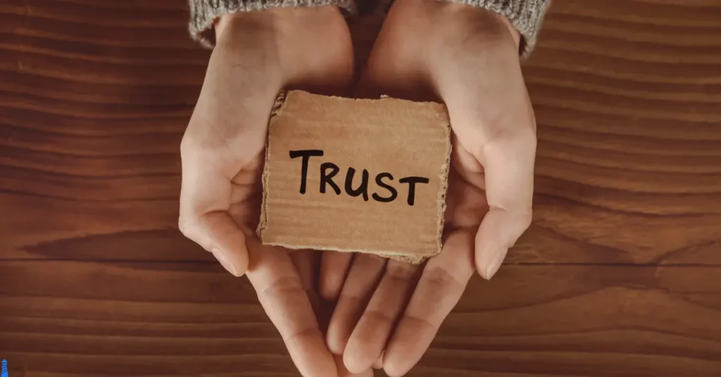 The word trust written on cardboard held by cupped hands