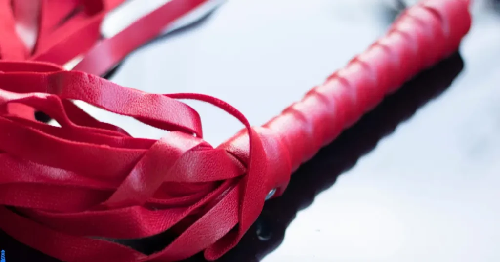 A red leather flogger on a white background