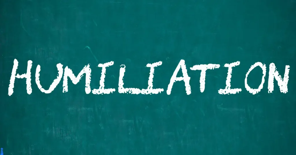 The word humiliation written on a chalkboard.