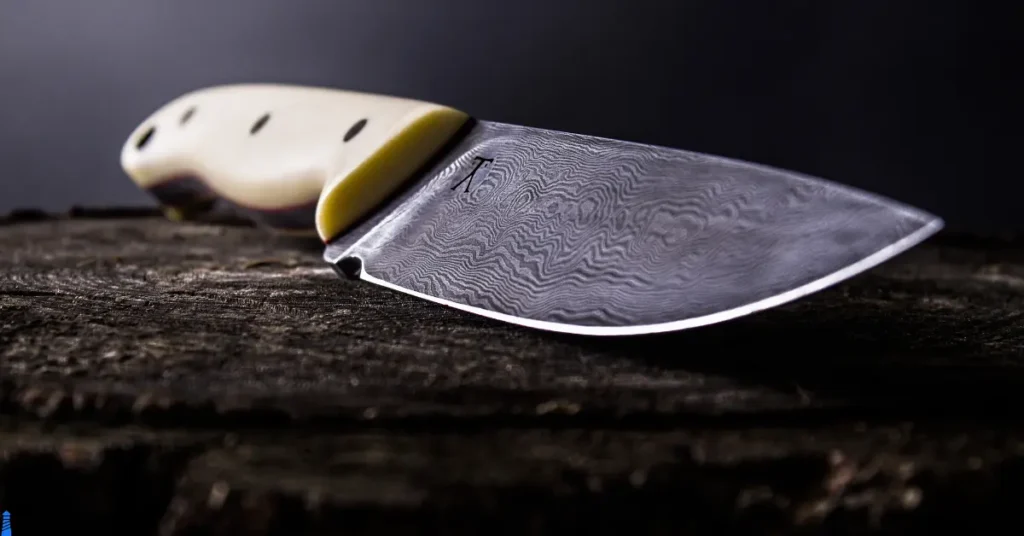 White handled knife with an intricate blade.