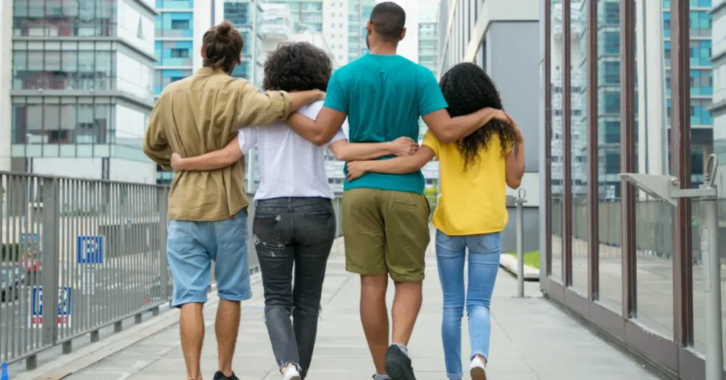 Four people walking with their arms around each other.