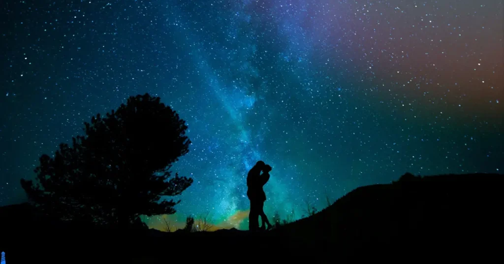 Couple kissing with the night sky and the Milky Way behind them.